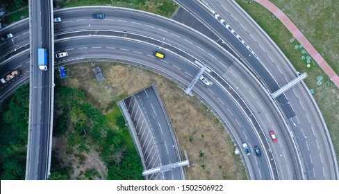 Ariel View Of Highway With Green Grass And Tunnels. Busy Traffic In Urban City.