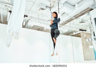 Ariel Yoga. Young Caucasian Woman In Sportswear Practicing Fly Yoga In Studio, Standing On The One Leg In White Hammock And Meditating