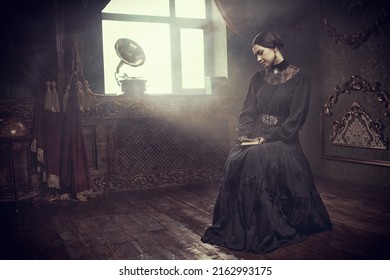 An aristocratic girl with black, gathered hair, and in a black dress, sits calmly in a vintage room with a book in her hands. The heroine of the novel, 19th century style. Copy space.