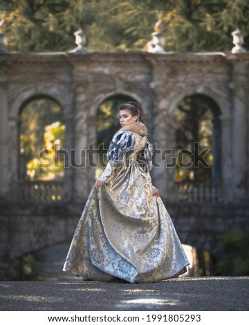 Aristocratic woman in a medieval dress against the background of the arches of an ancient castle