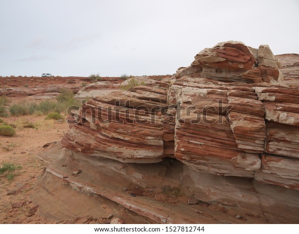 Arizona red\
desert landscape scenic view near Lake Powell, red rock strata,\
layered red rock formation, car in\
background