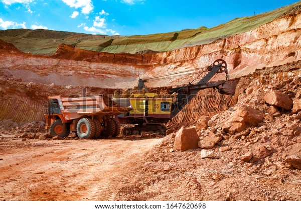 Arkalyk/Kazakhstan - May 15 2012: Excavator\
loads ore to Hitachi quarry dump truck. Aluminium ore mining and\
transporting. Bauxite clay open-cut quarry.\
