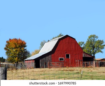 Arkansas Farm Site Has A Red Tin Covered Barn.  Tin Roof And No Loft Door.  Sky Is Blue.