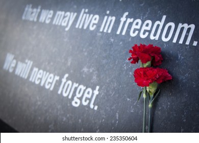 ARLINGTON, VA - SEPT 13, 2014: Red carnations laying against the granite wall of the Memorial Gateway entrance to the Pentagon Memorial dedicated to the victims of the September 11, 2001 attack.
