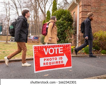 ARLINGTON, VIRGINIA, USA - MARCH 3, 2020: Democratic Primary Election Voters Arrive At Lyon Village Polling Place, Passing Photo ID Required Sign.