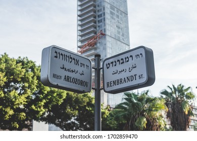 Arlozorov And Rembrandt Street Name Signs In Tel Aviv, Israel. Street Name Signs Are Most Often Posted At Intersections And Are Usually In Perpendicularly Oriented Pairs Identifying Crossing Streets