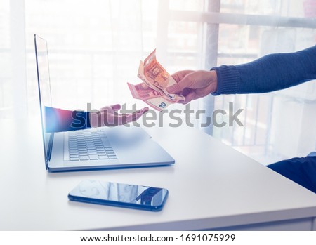 An arm comes out of a laptop to extort money from a person in front 商業照片 © 