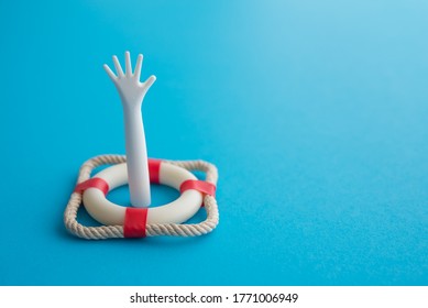Arm Emerging In Red Lifebuoy Or Lifebelt With Blue Background Copy Space. Investment Protection, Personal Loan And Life Or Health Insurance Concept. Risk Management Analysis And Planning.
