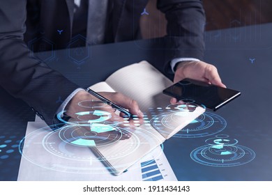 Arm in formal wear writing down some ideas using phone to create innovative software to provide a completely new high-tech service. Close up shot. Hologram tech graphs. Concept of Dev team