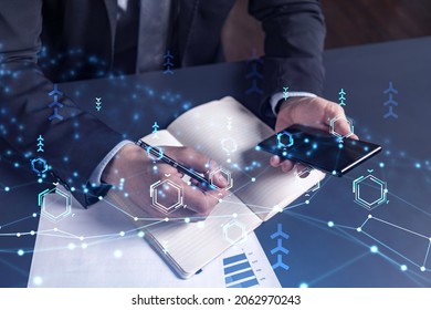 Arm in formal wear writing down some ideas using phone to create innovative software to provide a completely new high-tech service. Close up shot. Hologram tech graphs. Concept of Dev team - Shutterstock ID 2062970243
