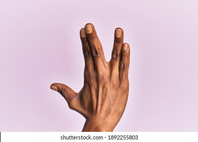 Arm And Hand Of Black Middle Age Woman Over Pink Isolated Background Greeting Doing Vulcan Salute, Showing Back Of The Hand And Fingers, Freak Culture 