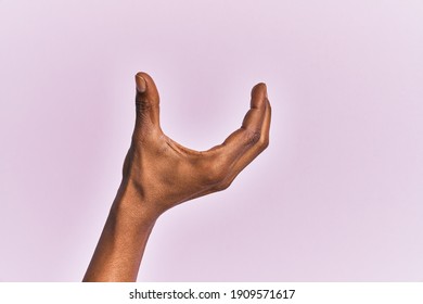 Arm and hand of black middle age woman over pink isolated background picking and taking invisible thing, holding object with fingers showing space 