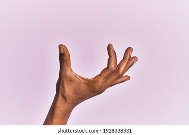 Arm and hand of black middle age woman over pink isolated background picking and taking invisible thing, holding object with fingers showing space 