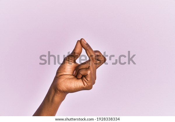 Arm and hand of black middle age woman over pink\
isolated background snapping fingers for success, easy and click\
symbol gesture with hand 