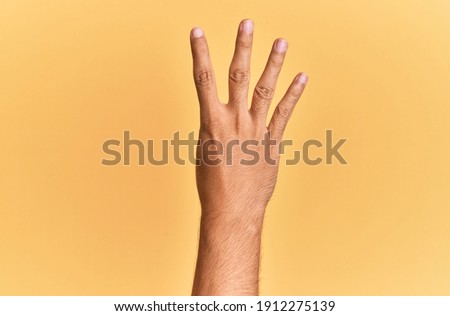 Arm and hand of caucasian man over yellow isolated background counting number 4 showing four fingers 