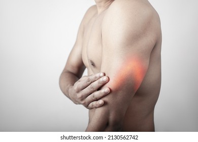 Arm injury, triceps pain, arm muscle inflammation, shirtless young man suffering from triceps muscle injury pain highlighted in red glow. - Shutterstock ID 2130562742