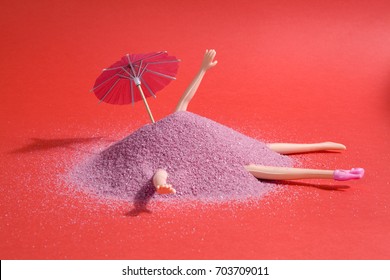 Arm and leg's doll emerging from a pile of pink sand as if it were hiding. Minimal funny and quirky design still life photography 