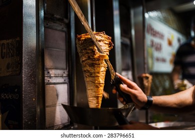 An arm moving to cut the kebab meat 