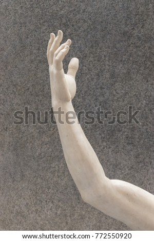 Arm sculpture on gray background.