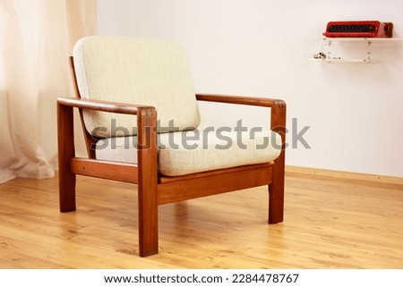 Armchair with Ottoman Danish Design in a Cosy Modern Furnished Living Room 60s Style Interior with a Wall Shelf and a Typewriter in the Background  Orange Lamp wooden floor