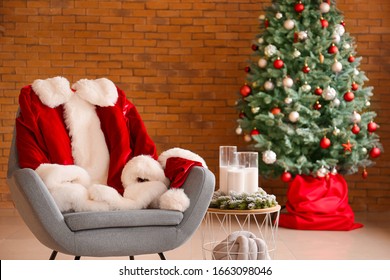 Armchair With Santa Claus Costume In Room Decorated For Christmas