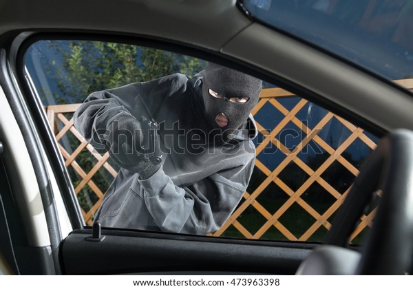 An armed man in the mask threatening pistol to the\
driver of the car