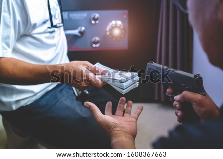 Armed robber using the gun to robbery the money with safe background.