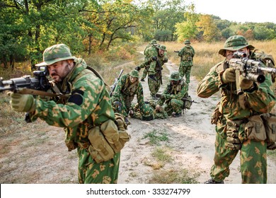 Armed soldiers evacuate the injured fellow  in forest