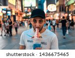 Armenian guy is eating fruit ice-cream cocktail in the middle of the street at night. Many people and night city on the background.