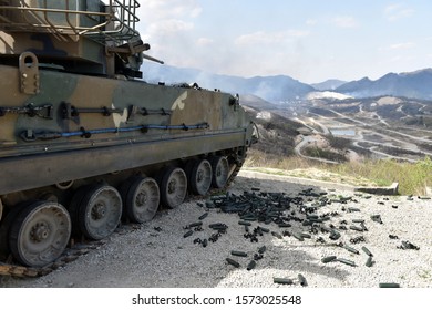 Armoured vehicle on top of a hill and casings laying around its tracks