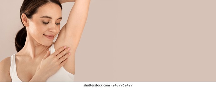 Armpit Depilation Concept. Happy Young Lady Looking At Her Smooth Underarms, Smiling Woman Wearing Underwear Standing With Hands Up Over Beige Studio Background, Copy Space