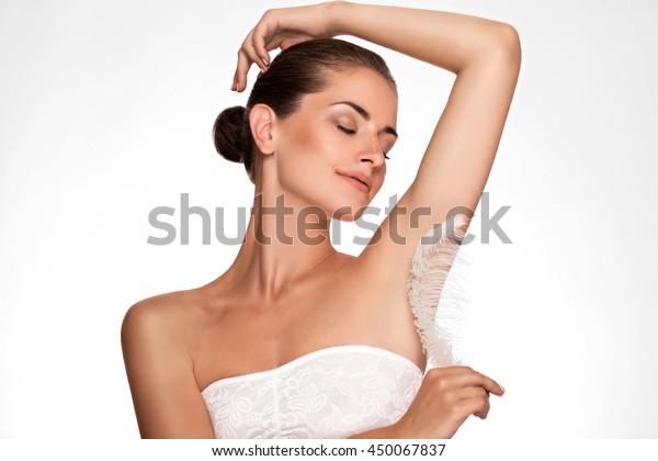 Armpit epilation, hair removal. Young woman holding\
her arms up and showing clean underarms, depilation smooth clear\
skin . Beauty portrait. armpit\'s care. Large white feather near \
skin