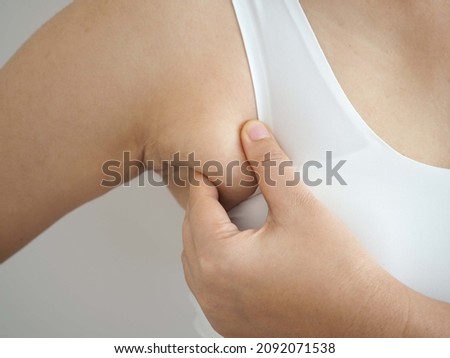 Armpit fat at asian woman between 30-40 years old dressed in a sporty  bra. closeup photo, blurred.