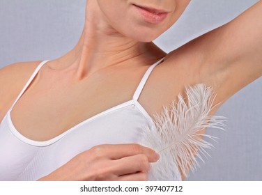 Armpit waxing, laser hair removal. Attractive female touching her skin with feather