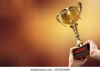 Arms raising the winning trophy - Shutterstock ID 1371527696
