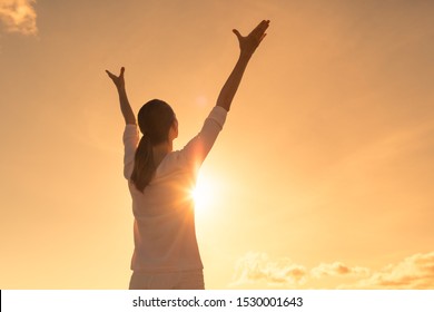 Arms up to the sunset feeling happy and free.
