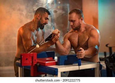 The Armwrestling. Two strong athletes in the gym have a train in arm wrestling. Bodybuilders armwreslers in athletic training room