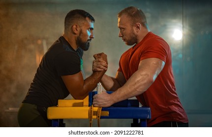The Armwrestling. Two strong athletes in the gym compete in arm wrestling. Bodybuilders armwreslers in athletic training room