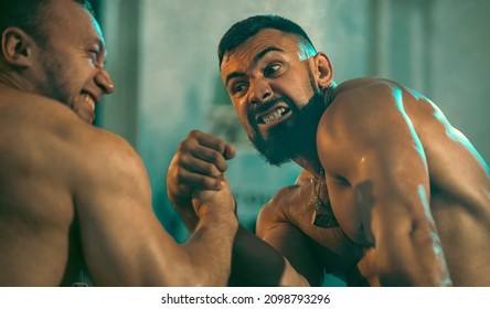 The Armwrestling. Two Strong Athletes In The Gym Compete In Arm Wrestling. Bodybuilders Armwreslers In Athletic Training Room