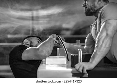 The Armwrestling. Two strong athletes in the gym compete in arm wrestling. Bodybuilders armwrestlers in athletic training room