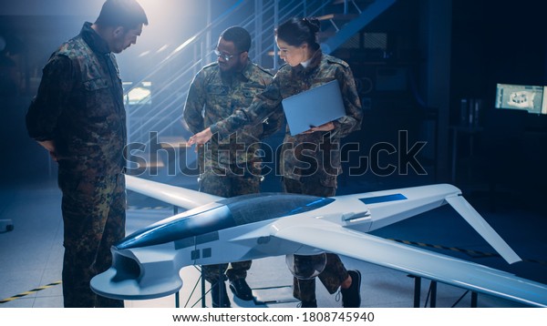 Army Aerospace Engineers Work On Unmanned Aerial\
Vehicle / Drone. Uniformed Aviation Experts Talk, Using Laptop.\
Industrial Facility with Aircraft for: Surveillance, Warfare\
Tactics, Air Strike