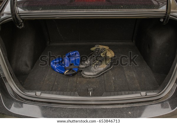 Army boots and boxing groves in the back of the\
car trunk,
