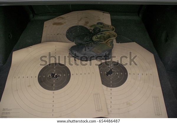 Army boots and paper target in the back of the\
dusty car trunk
