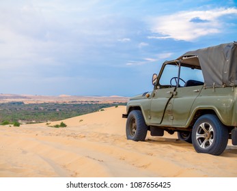 Army Green Off Road Car Vehicle Ready for Adventure on The Sand Dunes in Mui Ne, Vietnam on Desert Landscape and Blue Sky Background