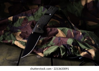 Army knife with black blade. Knife and army uniform. Camouflage and green box. - Shutterstock ID 2213633091