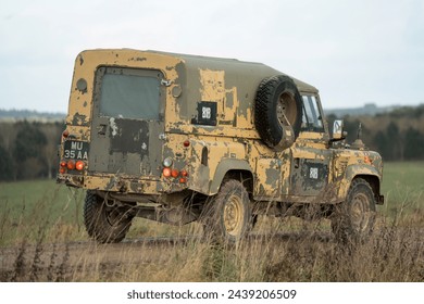 Army Land Rover Wolf Defender utility vehicle crossing grass meadows