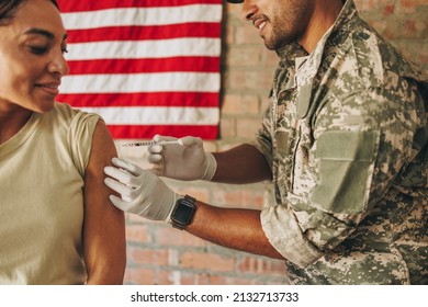 Army Medic Vaccinating A Female Soldier Against Coronavirus Disease. United States Military Physician Injecting A Female Soldier With The Covid-19 Vaccine In The Army Hospital.