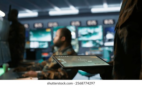 Army operative using tablet in command center housing operational missile defense system designed to intercept ballistic rockets. Close up of expert using tracking software on device, camera B