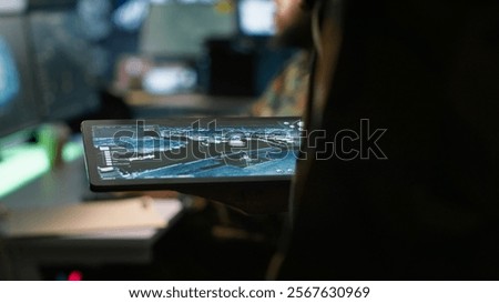 Army operative using tablet in command center housing operational missile defense system designed to intercept ballistic rockets. Close up of expert using tracking software on device, camera A