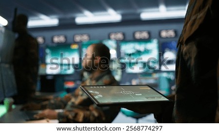 Army operative using tablet in command center housing operational missile defense system designed to intercept ballistic rockets. Close up of expert using tracking software on device, camera B